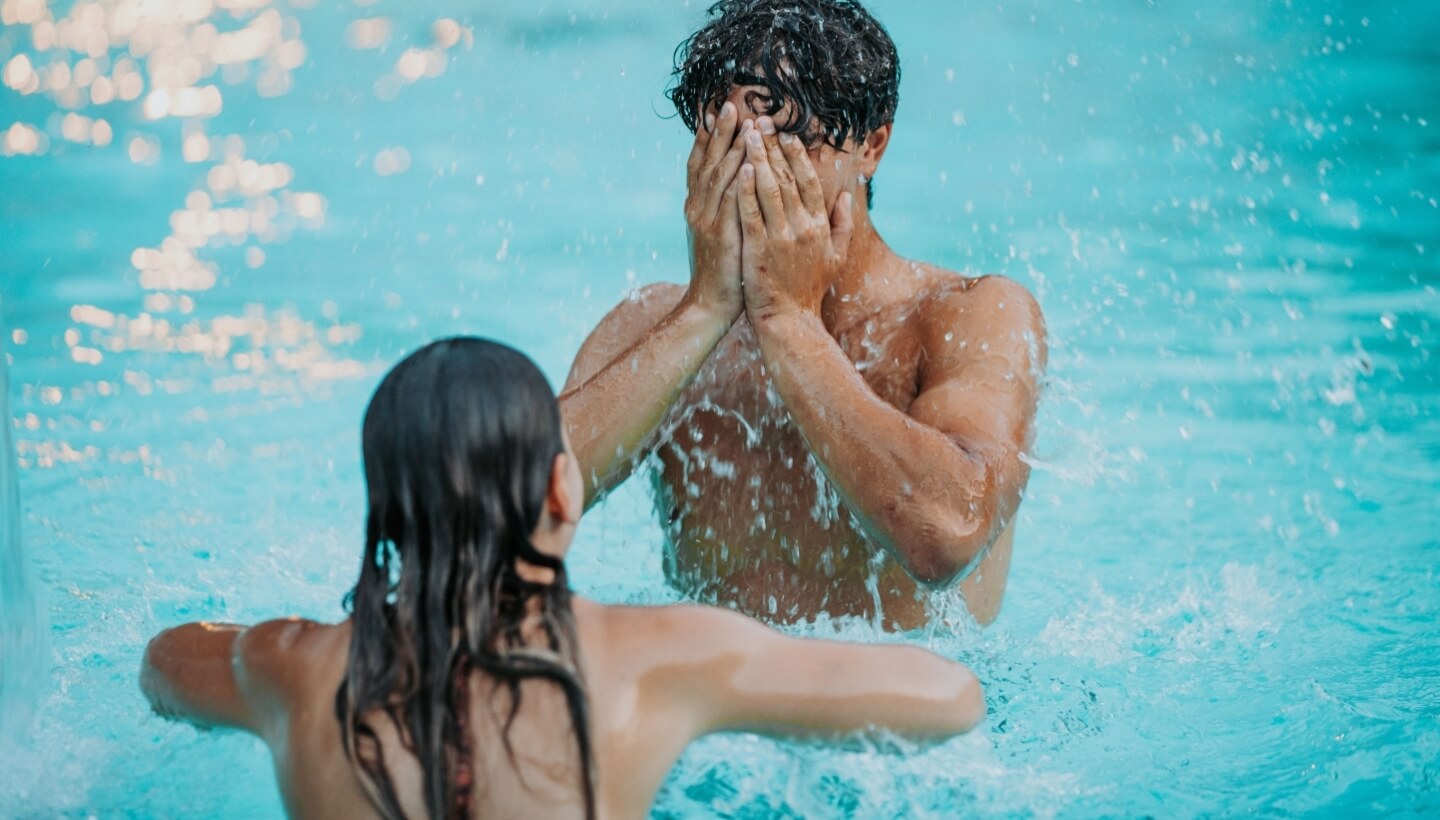Due persone in acqua blu, una copre il viso.
