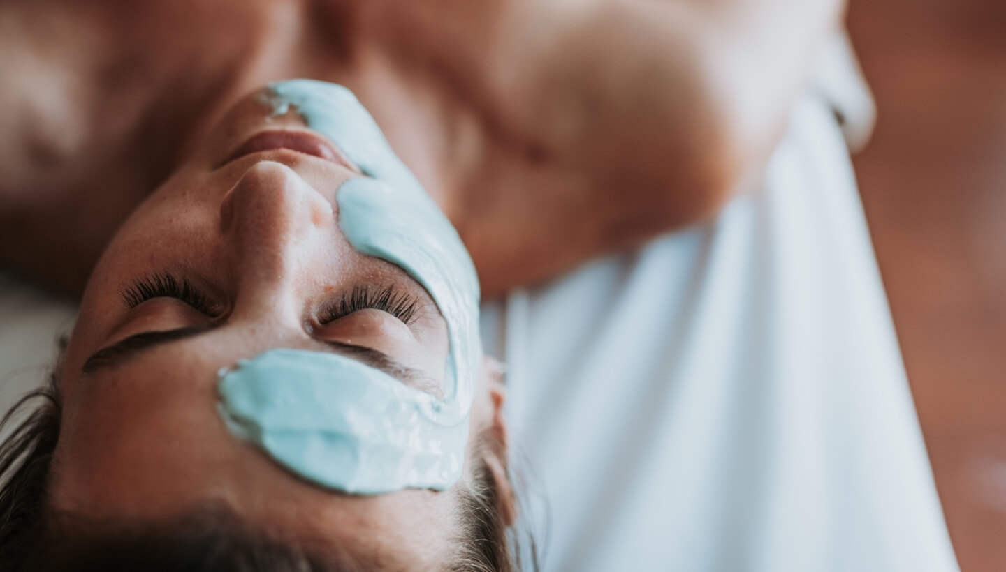 Person lying down with a light blue facial mask covering their eyes.