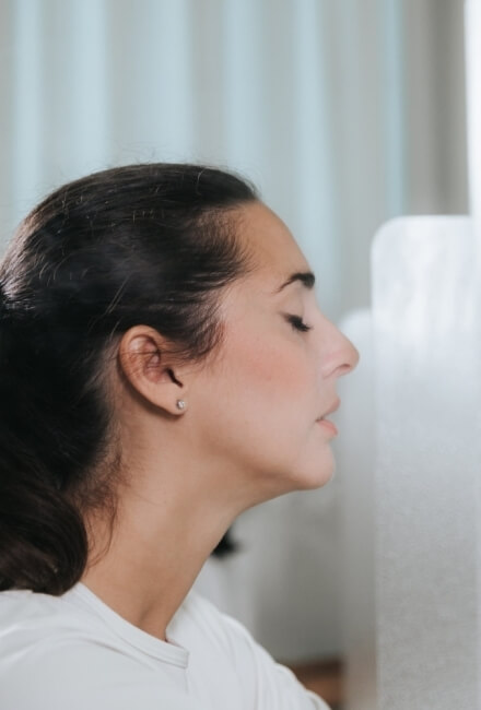 Profilo di donna con capelli scuri e occhi chiusi, indossa una camicia bianca.