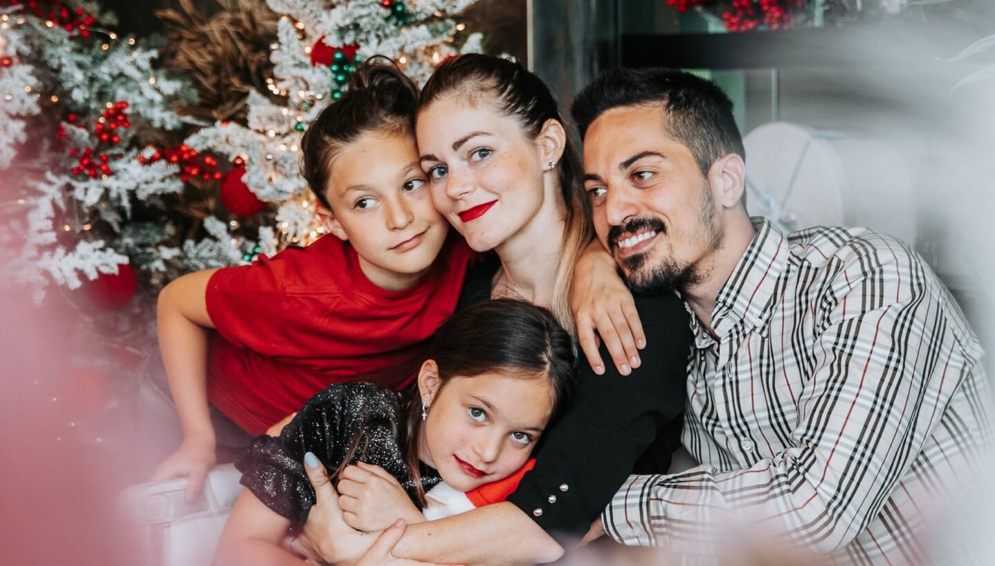 Famiglia davanti a un albero di Natale decorato.