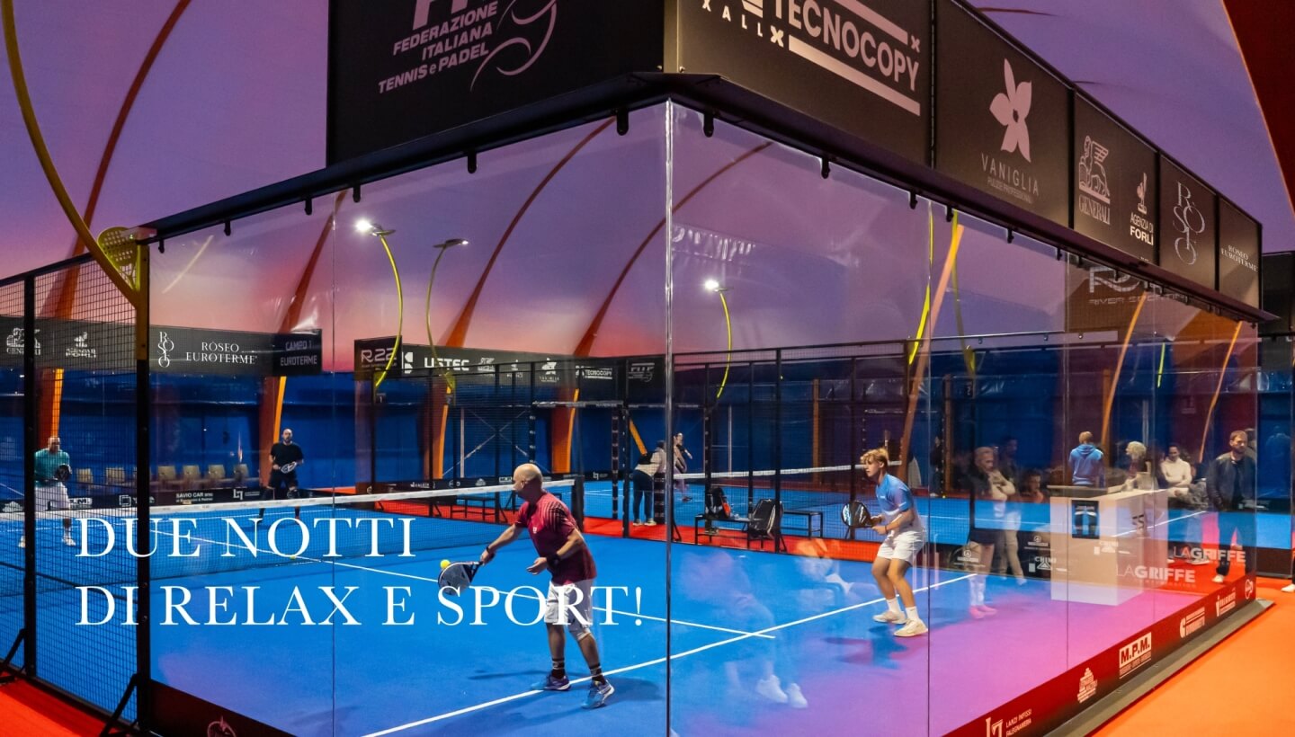 Due persone giocano a padel su un campo blu illuminato.