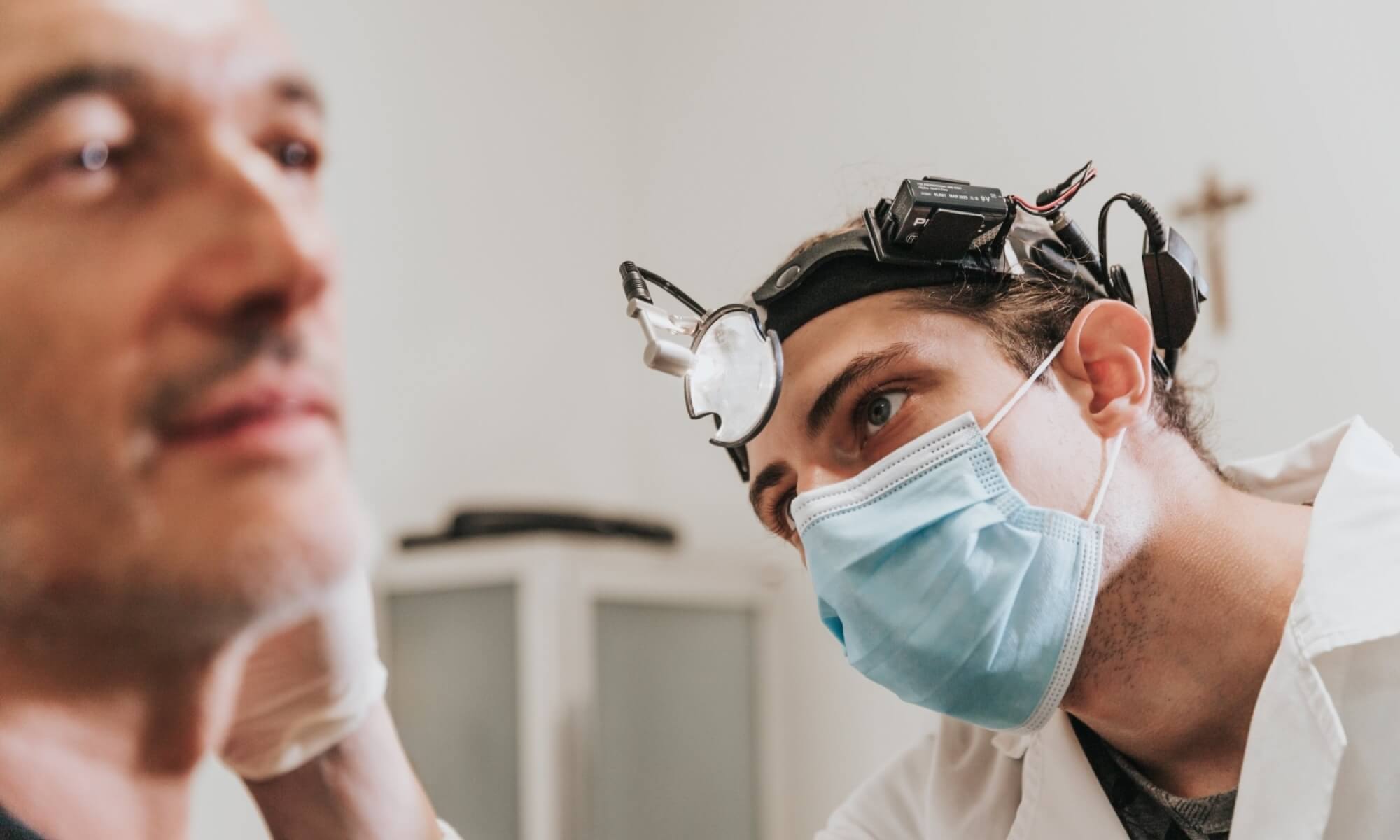 Persona con lampada frontale esamina il viso di un'altra persona.