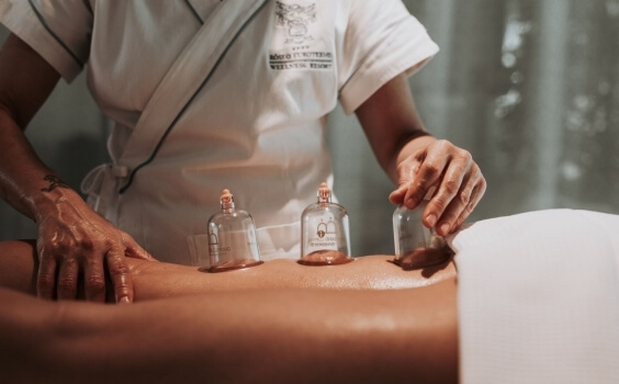 Therapeut mit Glaskopfmassage auf dem Rücken eines Patienten.