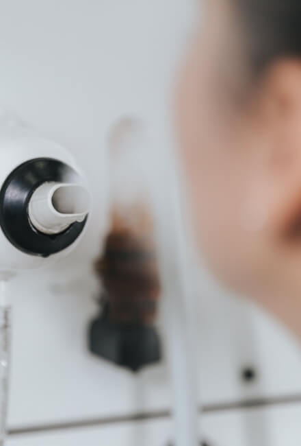 Un vaporizzatore bianco emette vapore vicino al viso di una persona.
