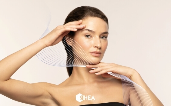 Frau mit dunklem Haar, RHEA COSMETICS-Logo, Wellenlinien überlagert.