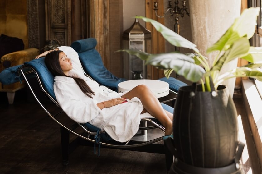 Donna in accappatoio bianco si rilassa su una chaise longue blu.