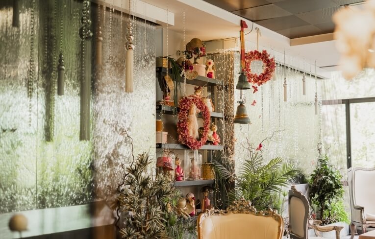 Scaffale decorato con bambole, ghirlande, campane e piante verdi.