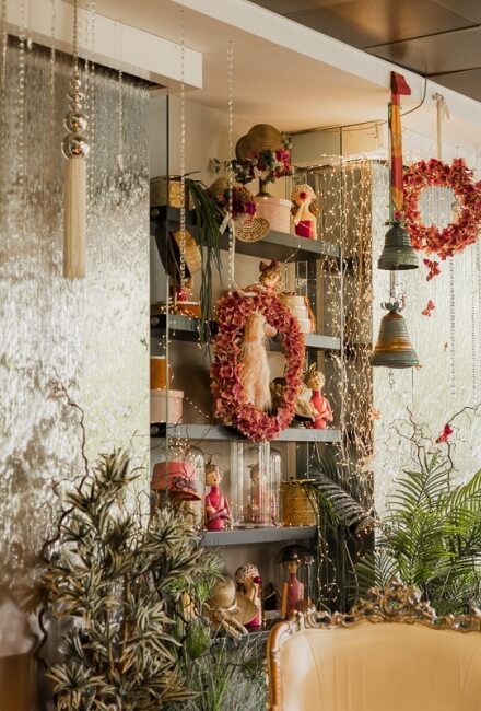 Decorative shelf with wreaths, dolls, figurines, plants, and lights.   Italian: Mensola decorativa con ghirlande, bambole, figurine, piante e luci