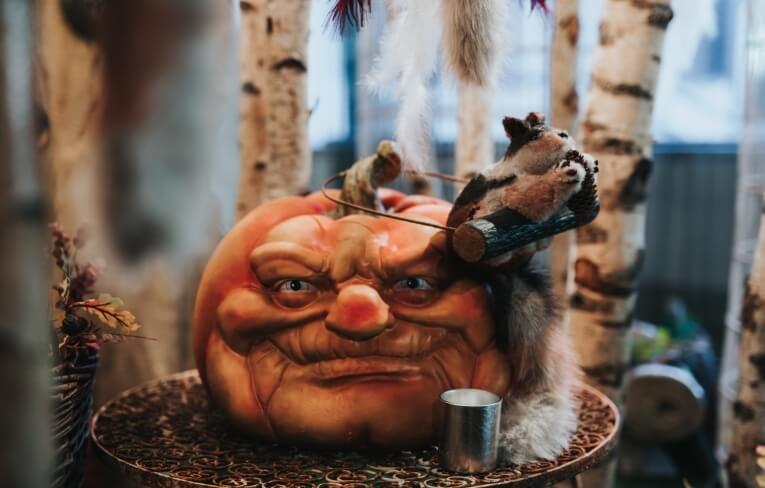 Zucca arancione intagliata su supporto, con scoiattolo finto e decorazioni.