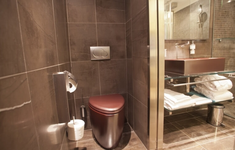 Bagno moderno con wc, lavabo, doccia e asciugamani piegati.