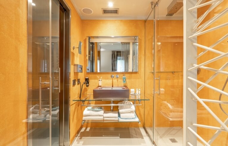 Bagno con pareti arancioni, doccia in vetro e area vanità.