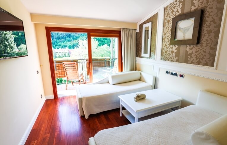 Hotelzimmer mit zwei Betten, Chaise Lounge und Balkon.