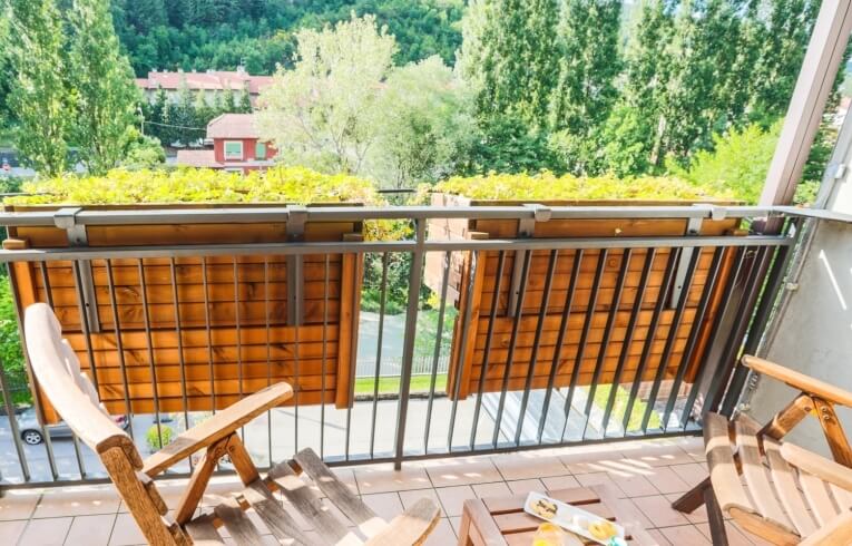 Balcone con sedie, tavolo, dolci e fiori gialli.