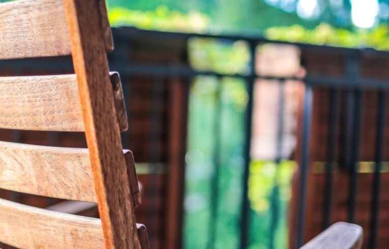 Sedia di legno con listelli orizzontali, sfondo sfocato di verde.
