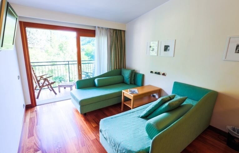 Camera d'hotel con balcone, chaise lounges e tavolino in legno.