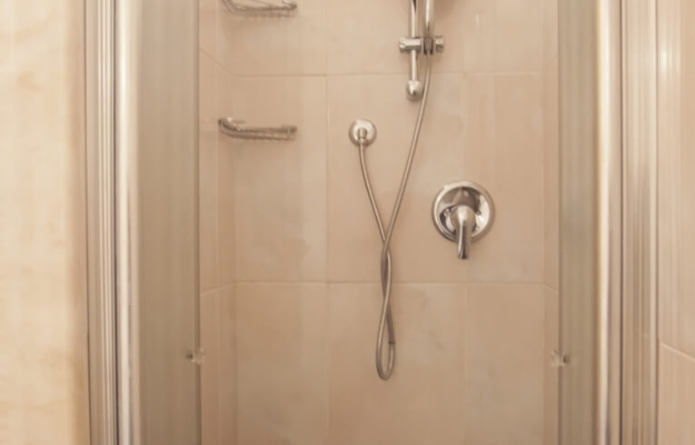 Doccia con pareti piastrellate, porta in vetro e accessori montati.