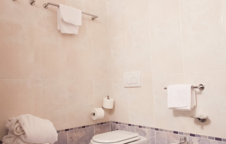 Bagno con lavabo, bidet, WC, asciugamani bianchi e carta igienica.