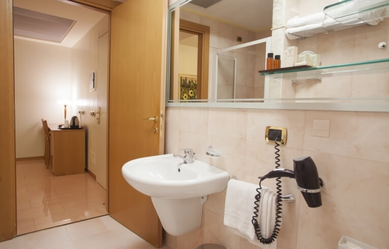 Hotel bathroom with sink, mirror, hairdryer, and toiletries.