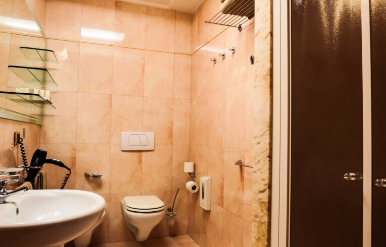 Modern bathroom with marble tiles, sink, toilet, and shower.