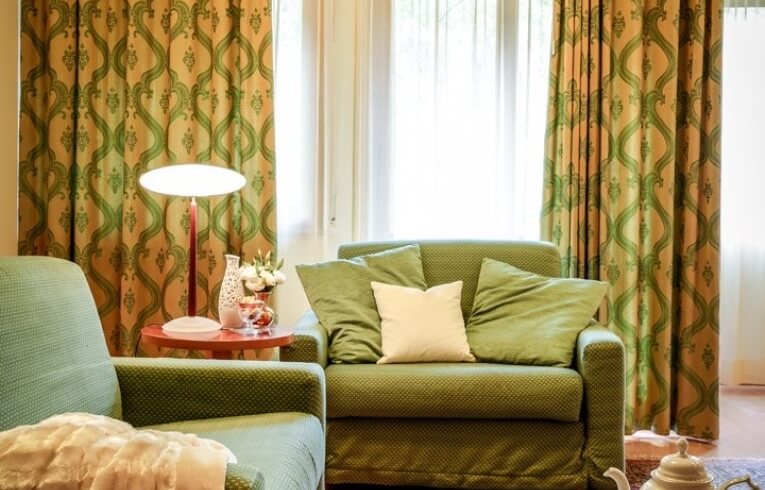 Green seating area with red accents and patterned curtains.