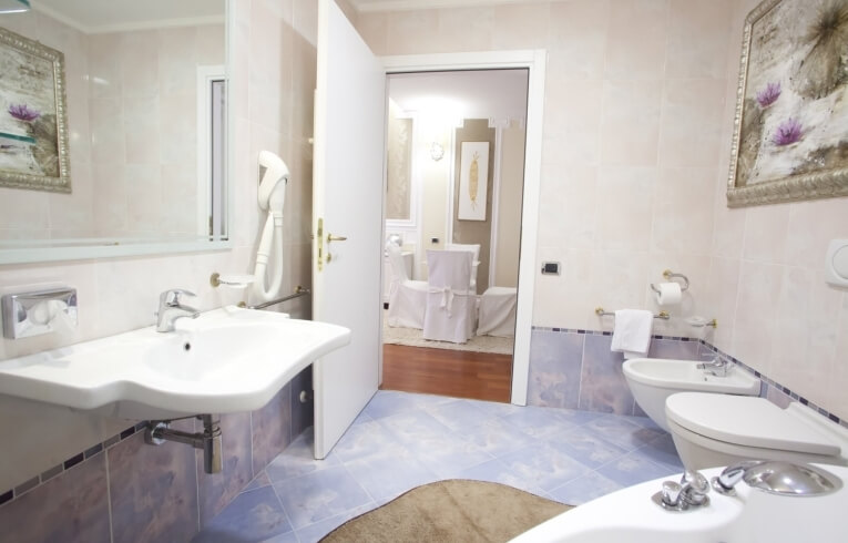 Hotel bathroom with sink, bidet, toilet, and open door.   Hotelbad mit Waschbecken, Bidet, Toilette und offener Tür.