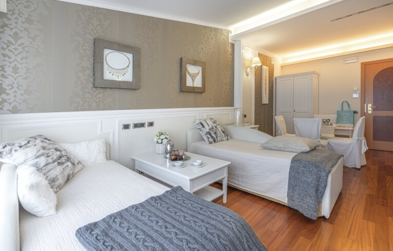 Hotelzimmer mit zwei Einzelbetten, Teeset und Sitzbereich.