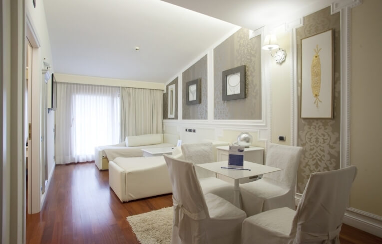 Helles Hotelzimmer mit weißen Möbeln, Holzboden und Kunstwerken.