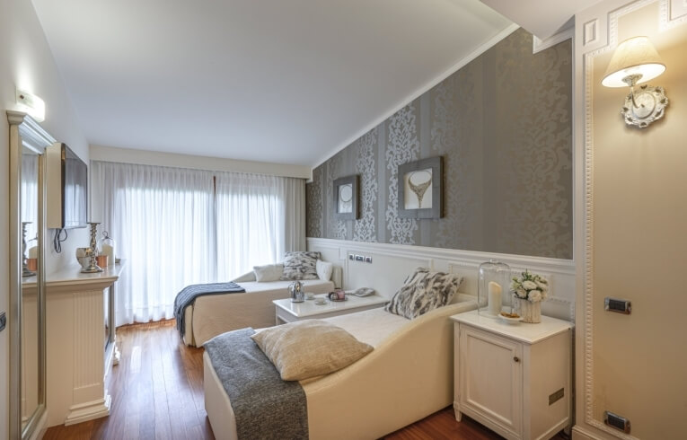 Hotelzimmer mit zwei Betten, Blumenvasen und dekorativen Bildern.