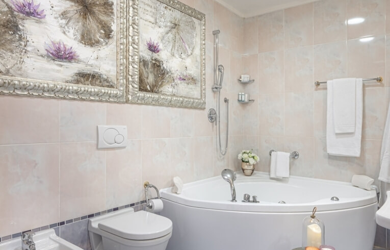 Hotel bathroom with corner bathtub, toilet, bidet, and floral decor.   Hotelbad mit Eckbadewanne, Toilette, Bidet und Blumendekor.