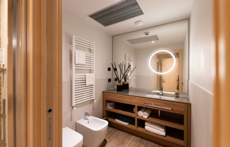 Modern bathroom with bidet, sink, heated towel rack, and mirror.