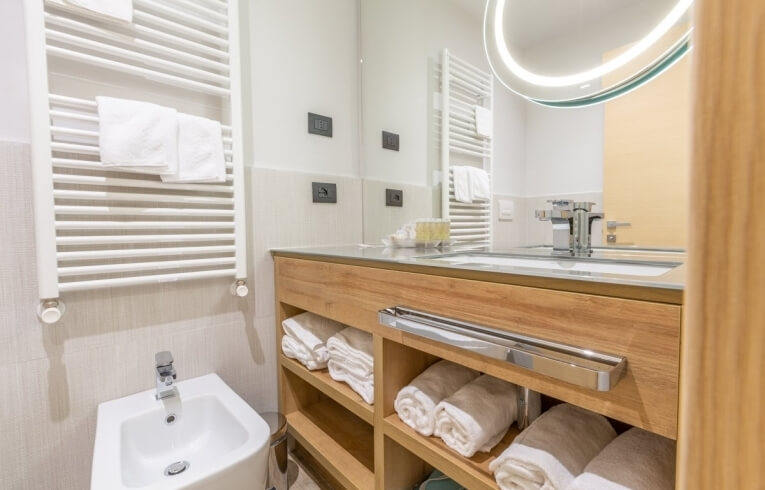 Modern bathroom featuring a bidet, wooden vanity, and towel warmer.