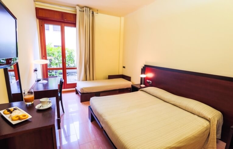 Camera d'hotel con due letti, scrivania e succo d'arancia.
