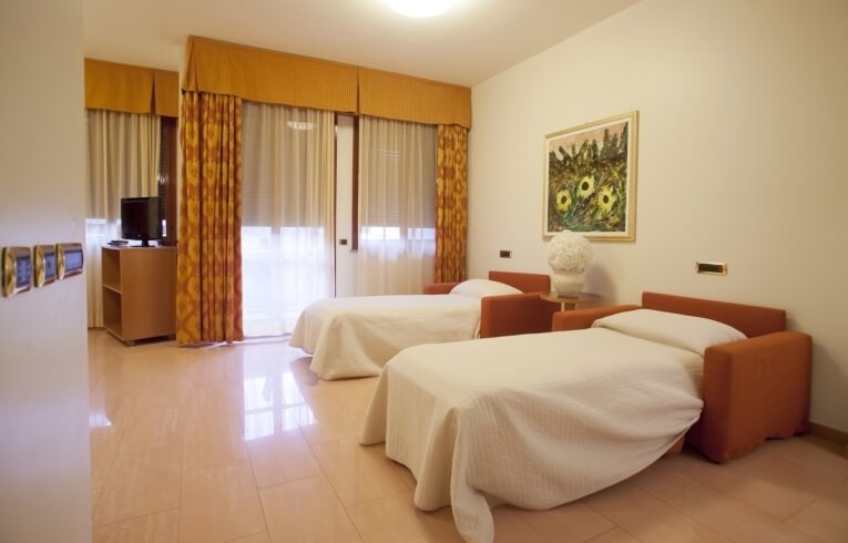 Hotel room with two orange armchairs as beds and a TV.