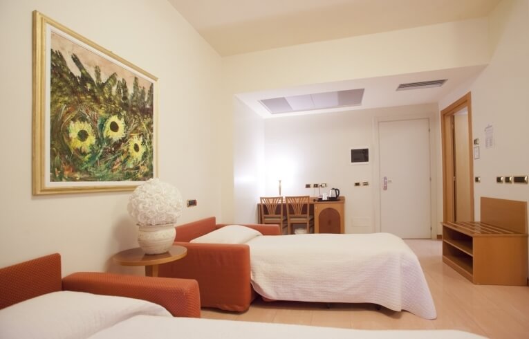 Hotel room with sofa beds, floral centerpiece, and sunflowers painting.