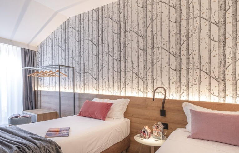 Hotel room with two beds, tree trunk wallpaper, and decorative birdhouses.