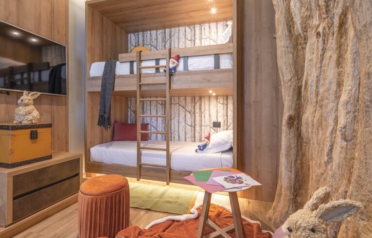 Bunk bed in hotel room with tree-patterned wallpaper and decor.