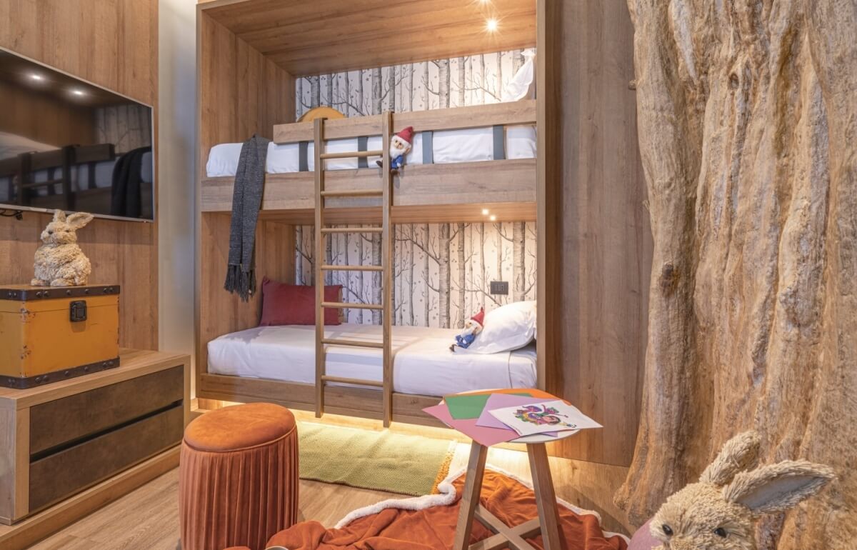 Camera d'hotel con letto a castello e decorazioni forestali.