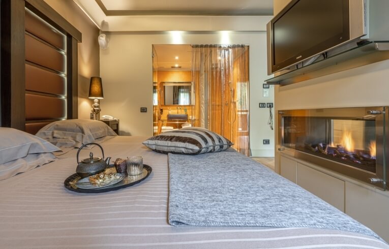Camera d'hotel con letto, camino, TV e area bagno.