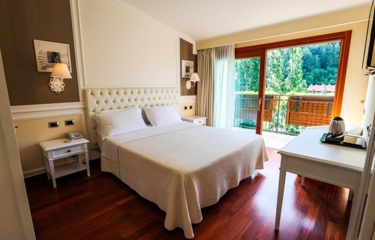Hotelzimmer mit Kingsize-Bett, Balkon und modernem Mobiliar.
