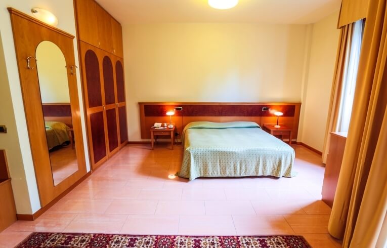 Cozy hotel room featuring a bed, nightstands, wardrobe, and curtains.