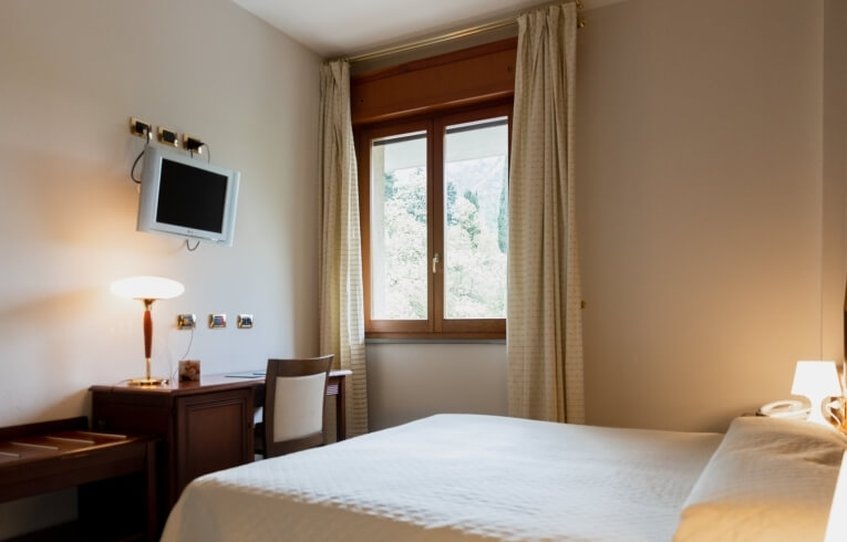 Camera d'hotel con letto, scrivania, TV e finestra.