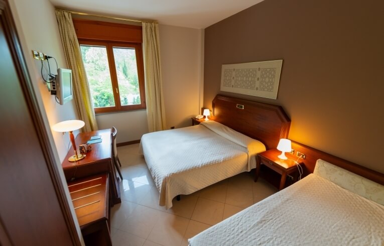 Camera d'hotel con un letto matrimoniale, un letto singolo e scrivania.