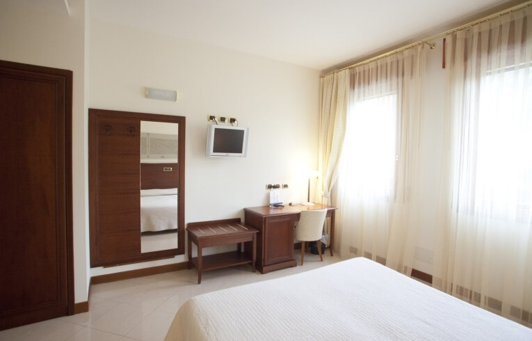 Camera d'hotel con specchio, TV, scrivania e letto.