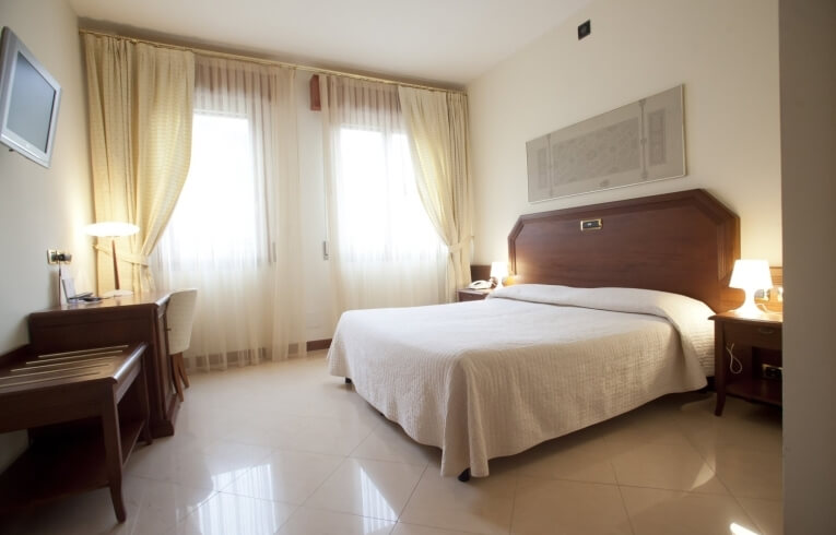 Camera d'hotel con letto king-size, scrivania e finestre con tende.