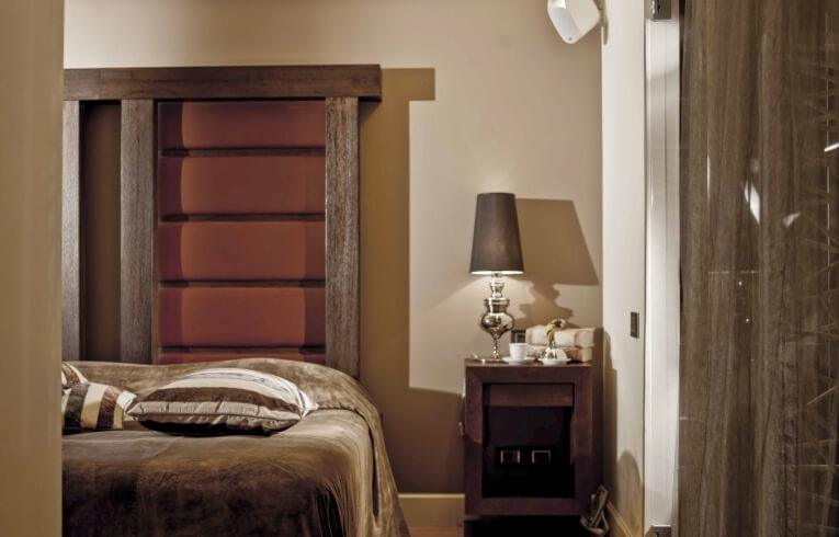 Camera d'hotel con letto, comodino e porta in legno.