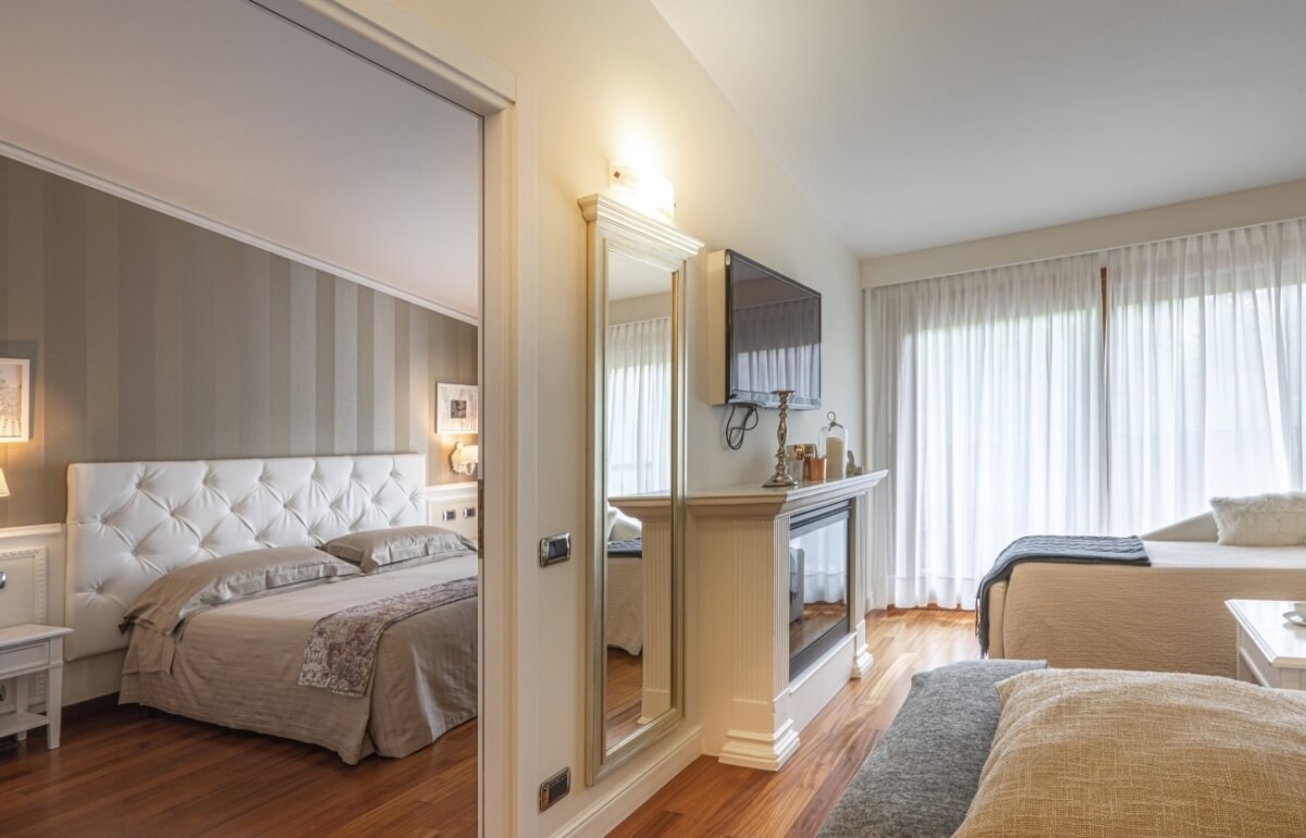 Camera d'hotel con letto, camino, TV e specchio a figura intera.
