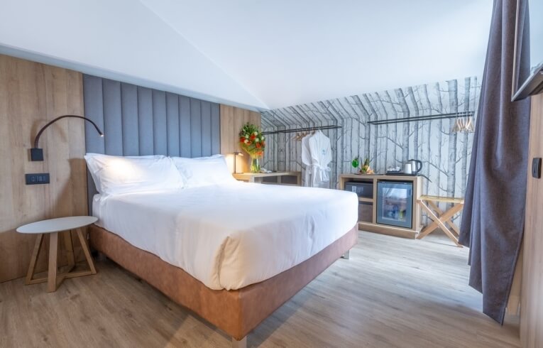 Cozy hotel room with a bed, mini fridge, and flowers.
