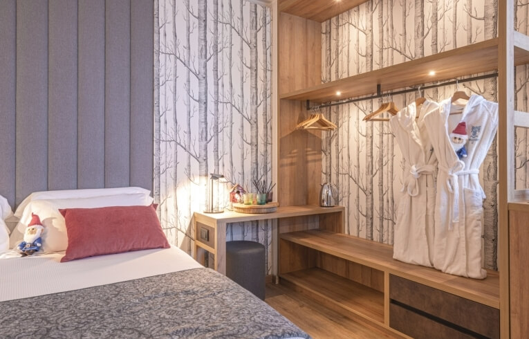 Hotel room with bed, desk, closet, and decorative elements.