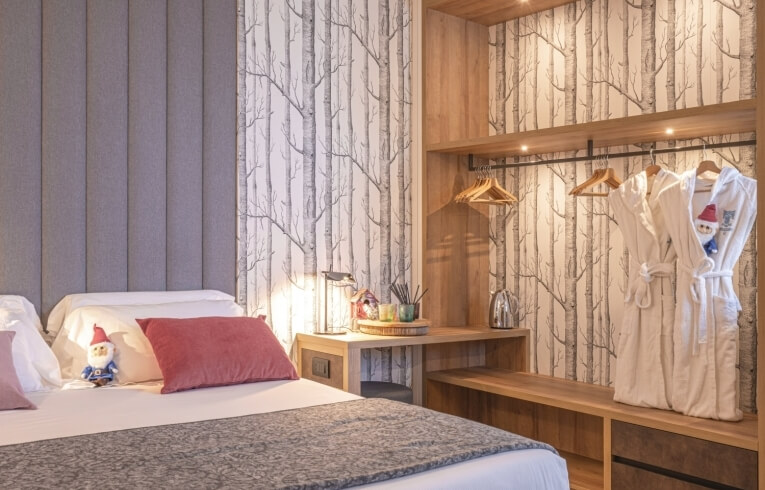Hotel room with a bed, wardrobe, and tree-patterned wallpaper.