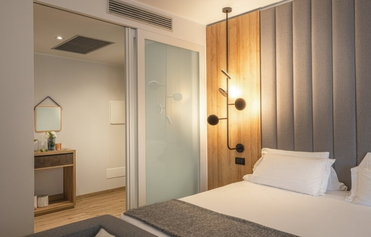 Camera d'hotel con letto bianco, parete in legno e vanity.
